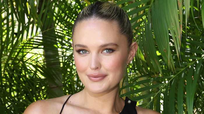 Georgina Burke poses in a black top and slicked-back hairdo and smiles slightly for the camera.